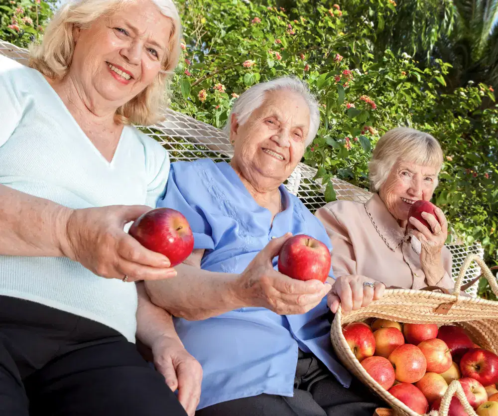Three assisted living female residents enjoying an outing to the apple orchard