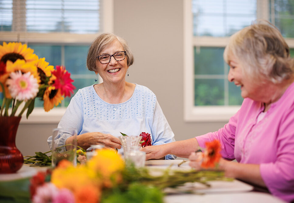 Two senior residents working on flower arrangements.