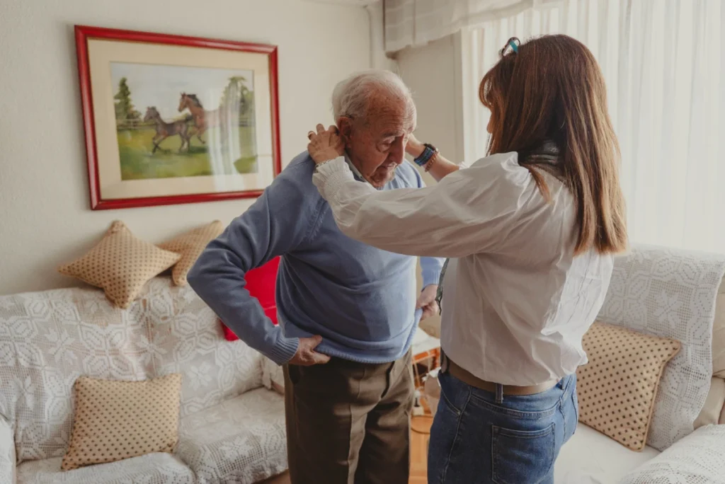 Caregiver helping senior man get dressed